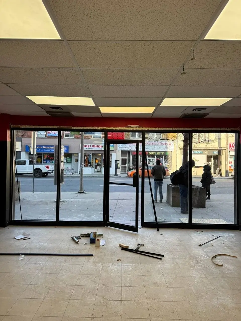 New aluminum storefront frame, door and glass installed in the Brampton plaza unit; tools remain on site.
