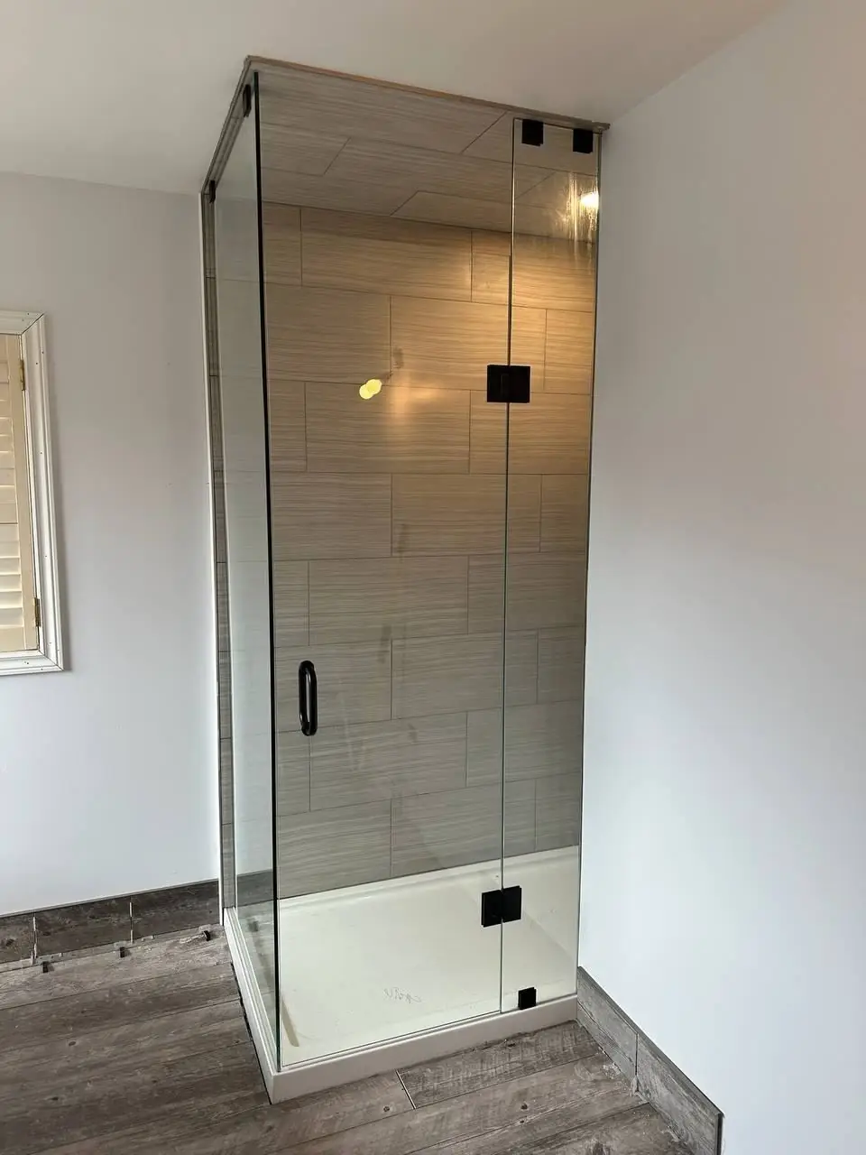 Custom frameless shower glass installed around finished tile and bench in Milton