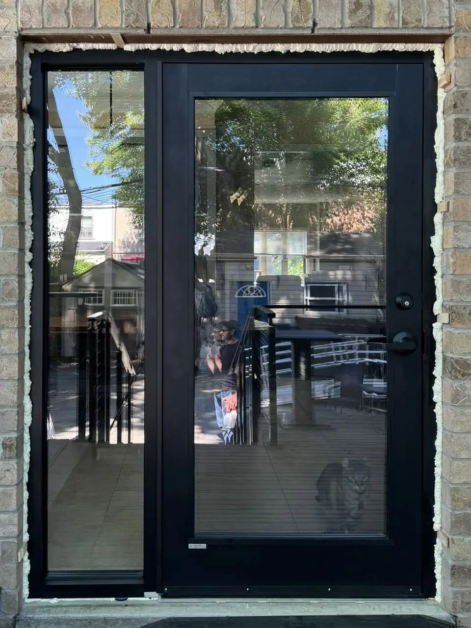Installed black garden door and full-height sidelight viewed from outside, with perimeter finishing still visible in Newmarket.