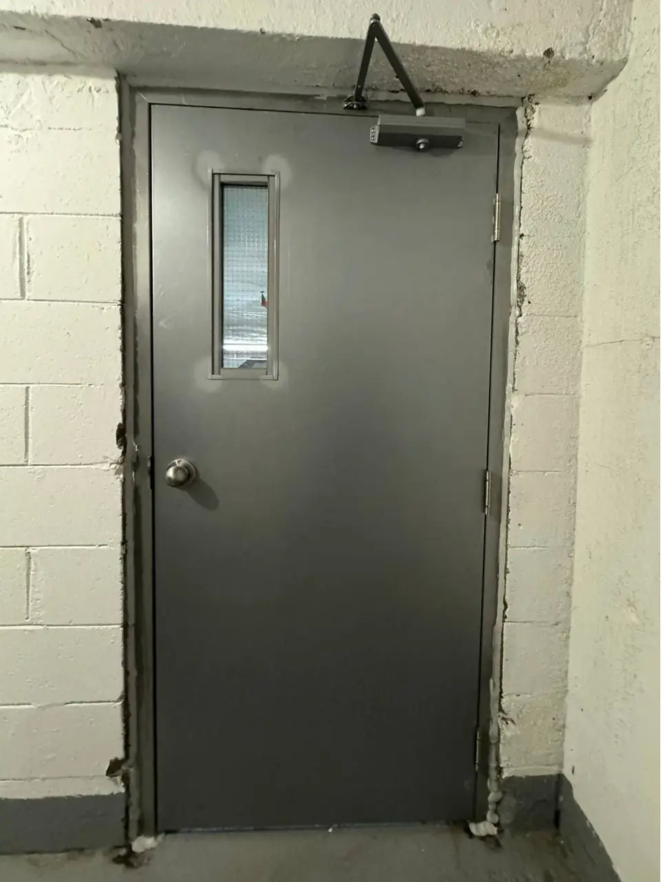 King City commercial steel door with GPW wired-glass vision lite and surface door closer visible.