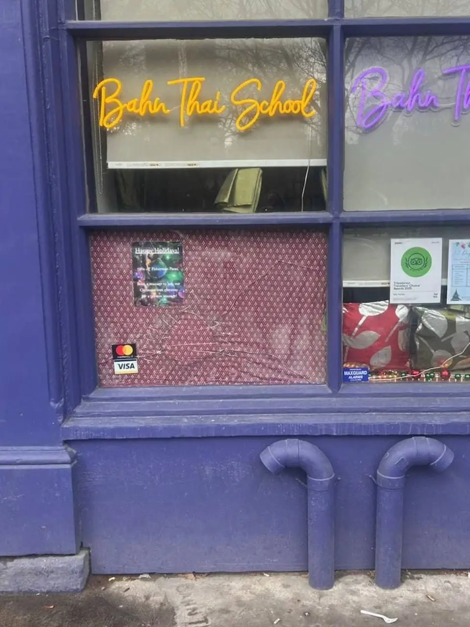 Boarded storefront window at Bahn Thai Spa near St. James Park after glass damage