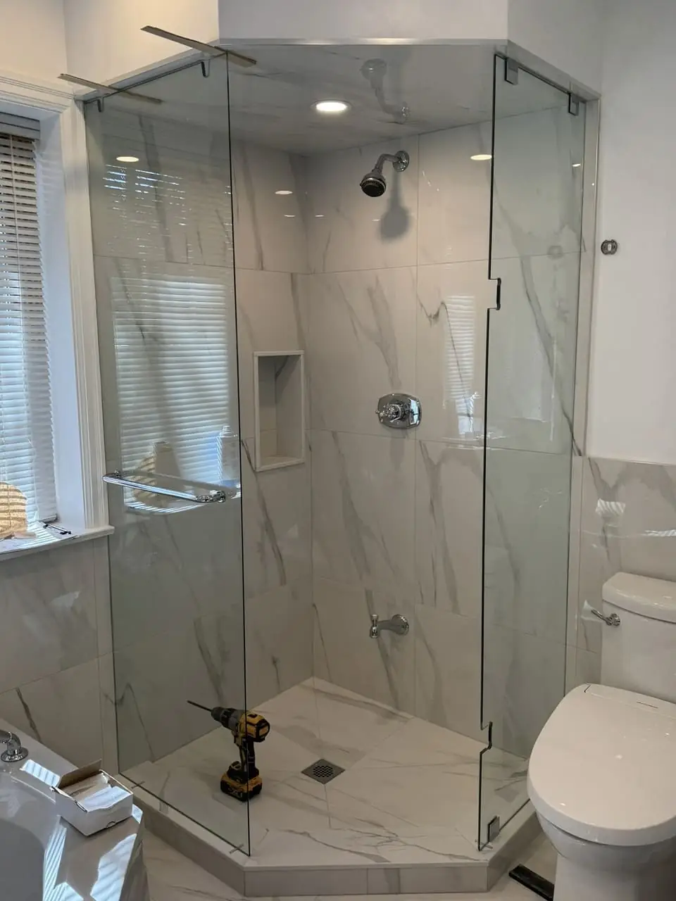 Richmond Hill neo-angle shower glass and door in position during installation, with tools still on the shower base.