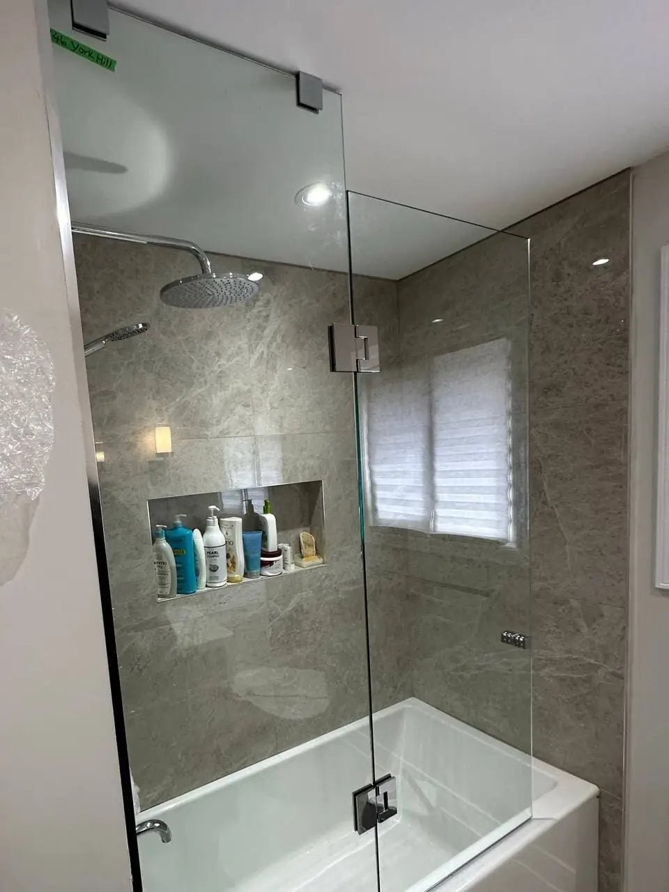 Finished frameless bath-glass installation in Uxbridge and Scugog, viewed from one side.