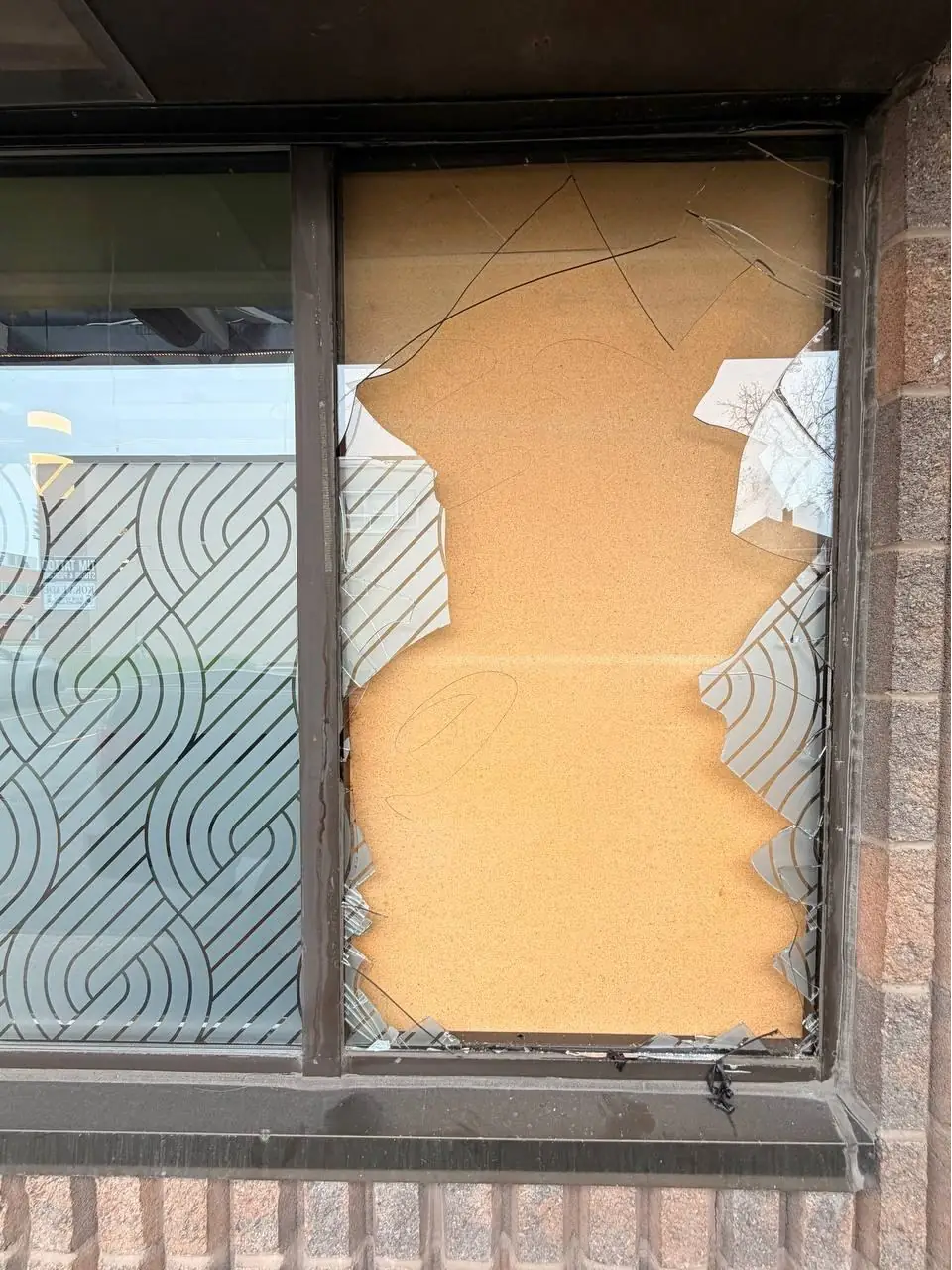Boarded broken storefront window in Burlington before glass replacement