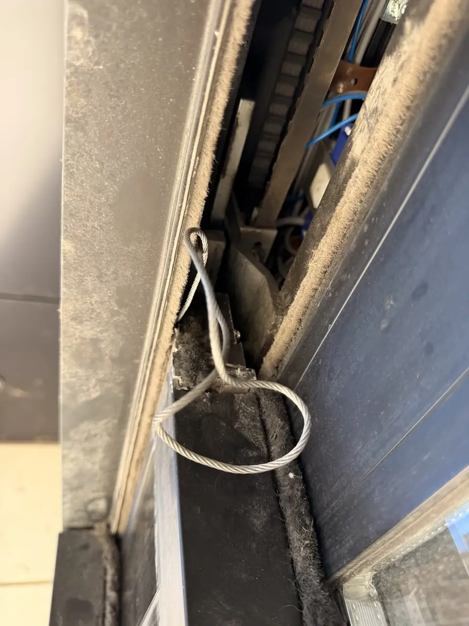 Broken steel cable inside an automatic telescopic sliding door mechanism in Downtown Toronto