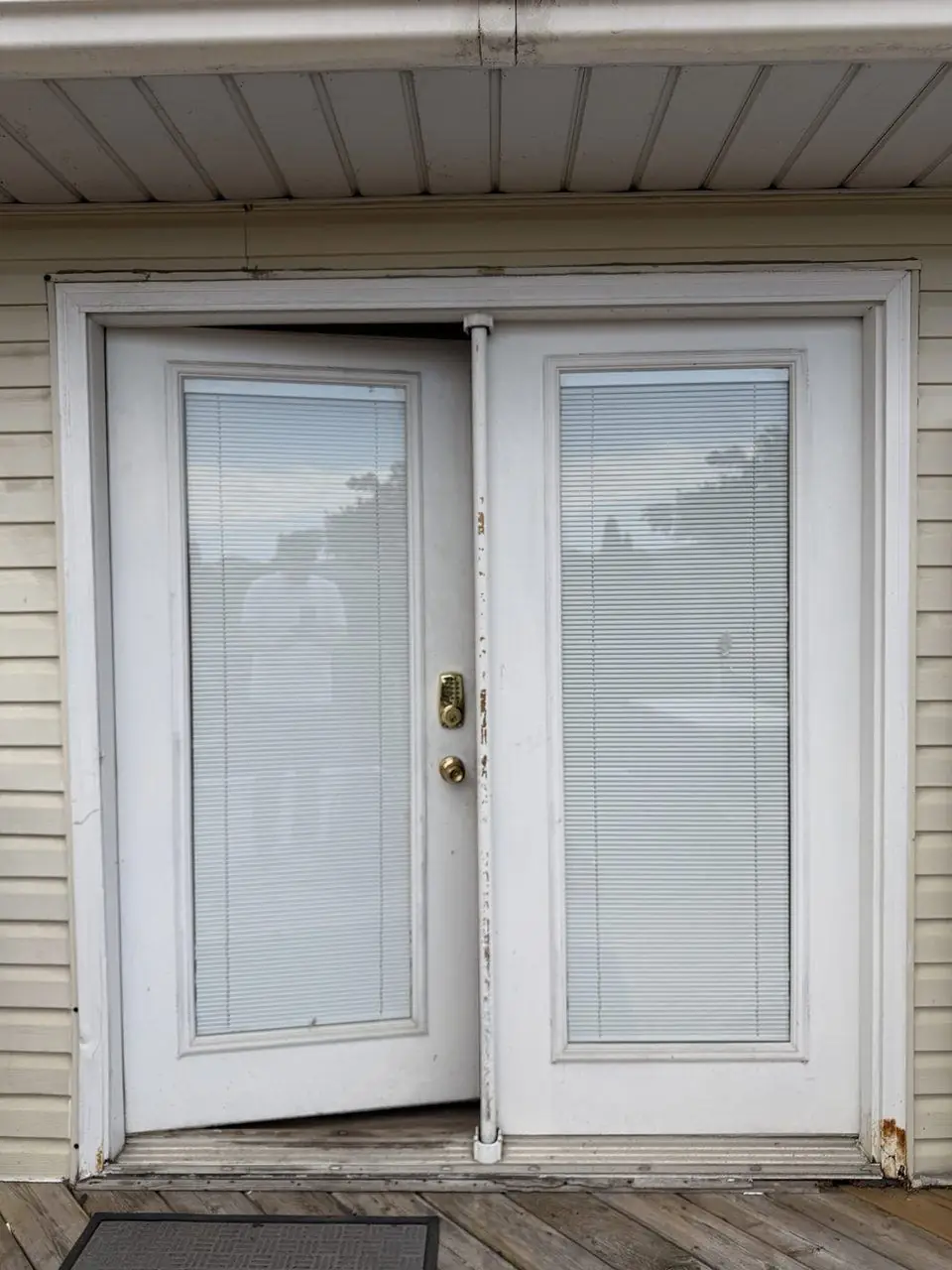 Old white French patio doors before replacement with built-in blinds upgrade planned