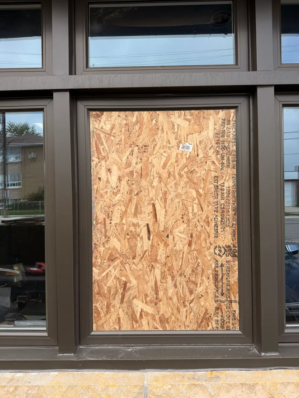 Auto repair shop window secured with plywood board-up in Mimico before permanent glass replacement
